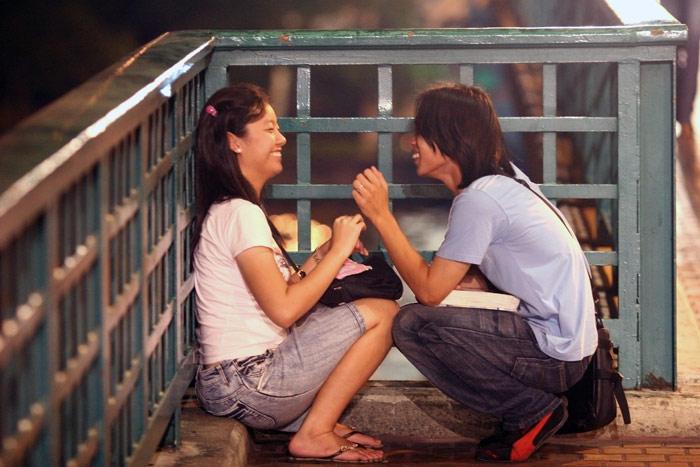 A young couple share a laugh. With nowhere to go - they can hardly hang out at either of their parents' houses, they are left to relax in public.