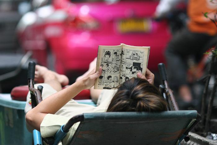 Right on Sukhumvit, a vendor takes a break and gets stuck into the latest comic. Thais of all ages adore comic books and it is not unusual to see women well into their 30s sitting on the skytrain enthralled by their comic!