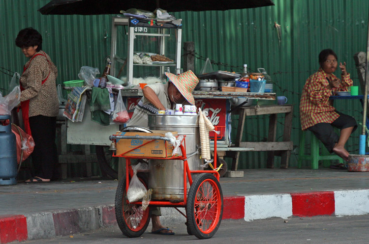 Near the Patumwan intersection in central Bangkok, an ice-cream vendor is watched by his fellow countrymen.